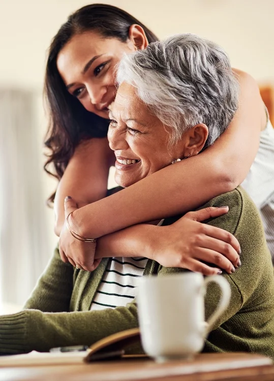 adult daughter hugs senior mother from behind