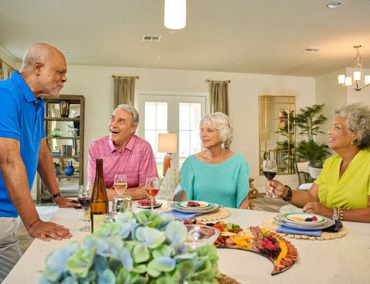 group of seniors gather in a villa home for snacks, drinks, and games