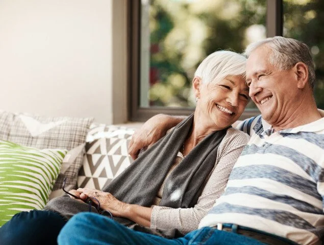 senior couple snuggles on outdoor couch at their home