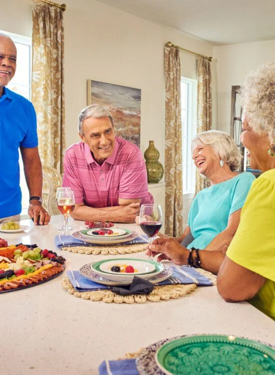 group of senior friends enjoy wine and dinner together in one of the villas at Village on the Green Senior Living Community