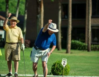 group of senior friends playing golf at their senior community celebrate a hole-in-one