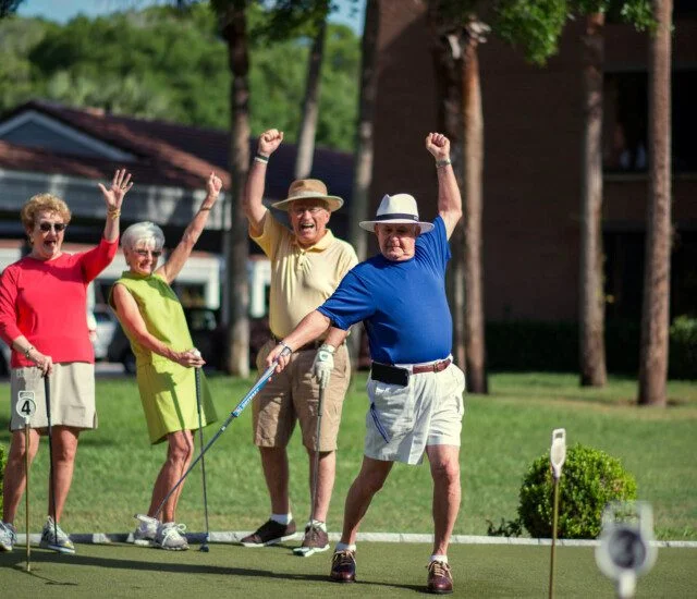 group of senior friends playing golf at their senior community celebrate a hole-in-one