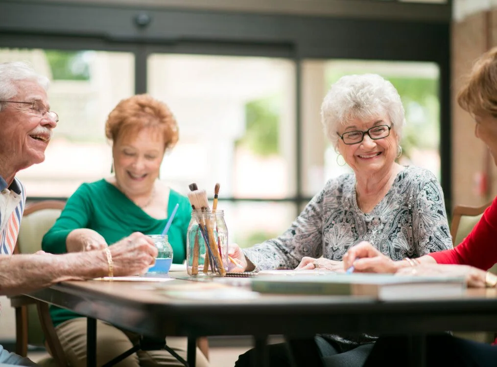 group of happy senior friends smile during a painting class at their senior living community