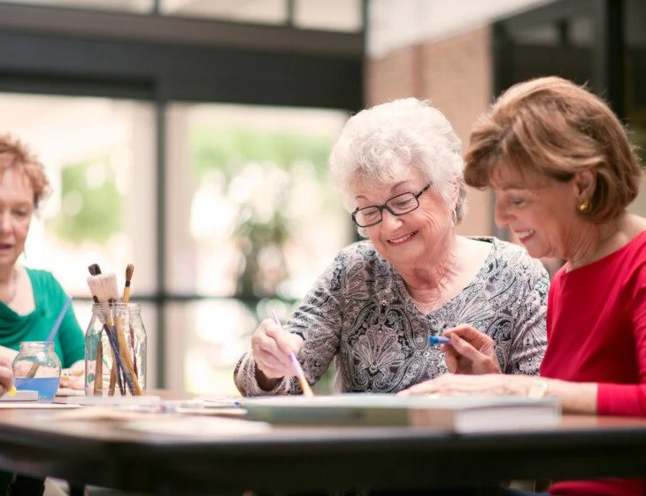 group of senior women smile while enjoying a painting class