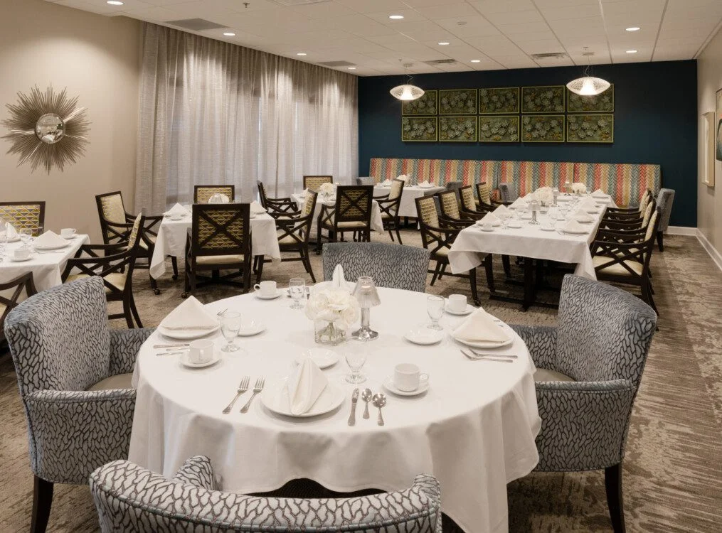 elegant formal dining room with tables and chairs at Village on the Green Senior Living Community