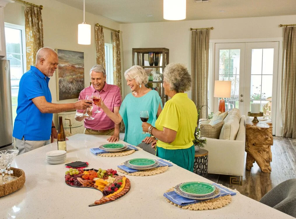 group of senior friends enjoy wine and dinner together in one of the villas at Village on the Green Senior Living Community