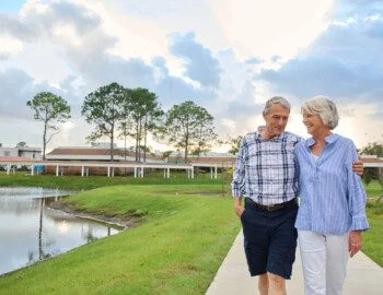 VOTG Selects R1 (1) Page 17 Image 0001 senior couple walks during sunset along a scenic path by the water at Village on the Green Senior Living Community