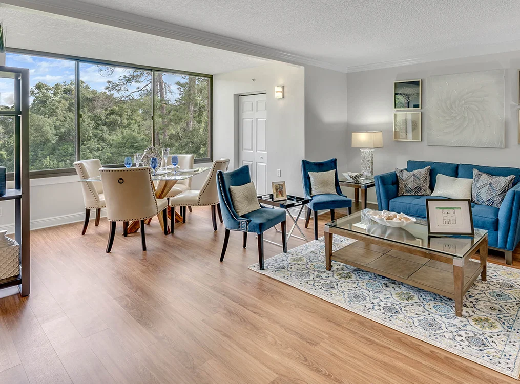 Modern living and dining area with blue accents and large window view.