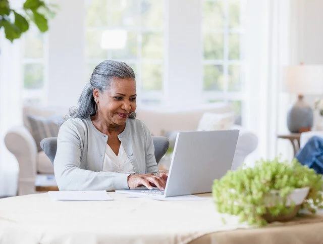 The mother sits at her computer answering emails to her friends.