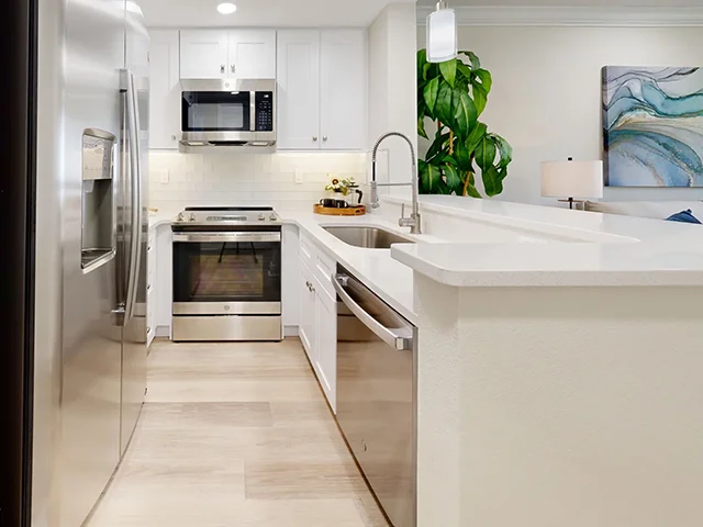 Modern kitchen with stainless steel appliances and white cabinets.