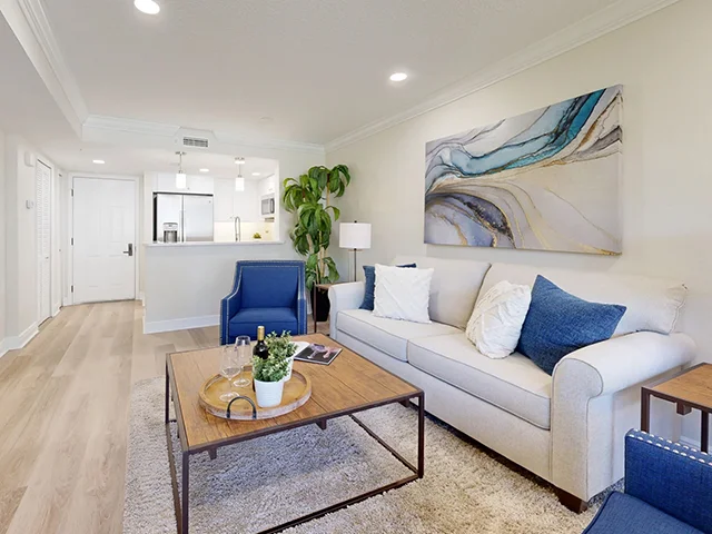 Modern living room with blue chairs, beige sofa, and abstract wall art.