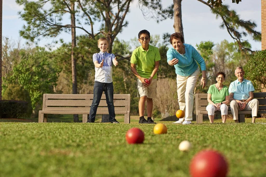 Resident at Village on the Green playing bocce balls with grandchildren.