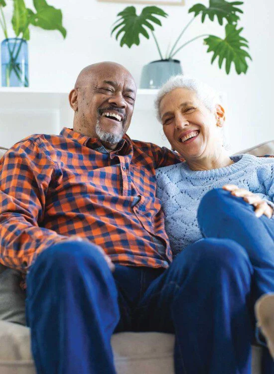 Older couple smiling together on a sofa.