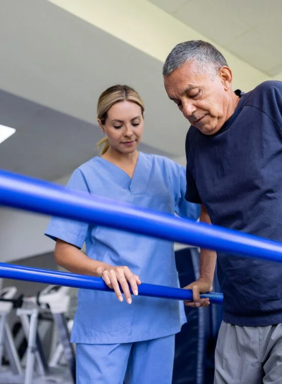 Physical therapist assisting man with parallel bars.