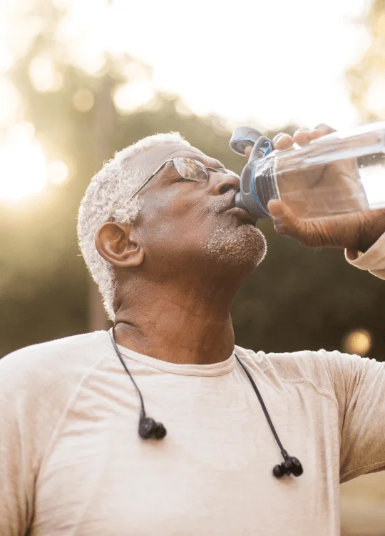 Man drinking water from a bottle outdoors.