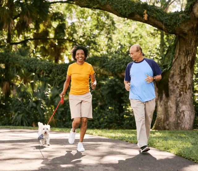 Man and woman walking outside with dog
