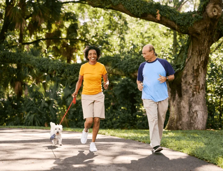 Man and woman walking outside with dog