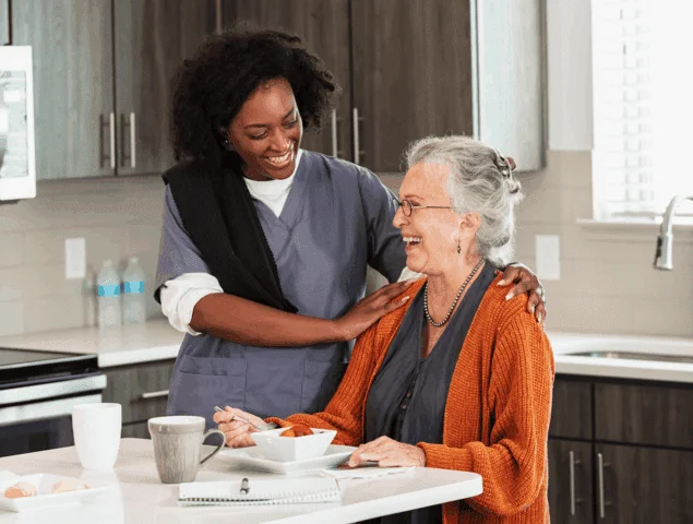 resident enjoying a meal with the assistance of a staff member