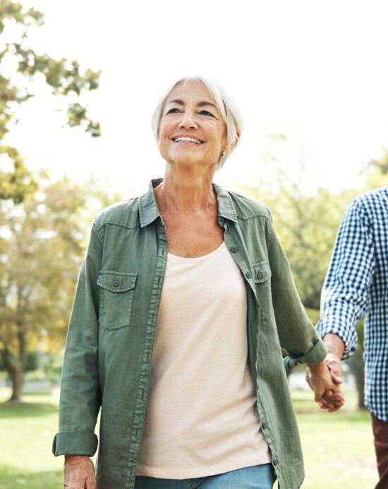 senior couple smiles and walks along scenic outdoor path