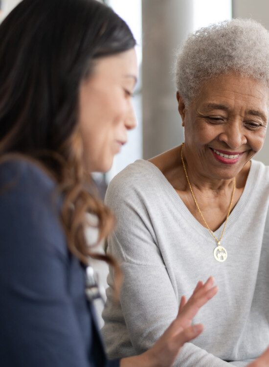 senior woman is shown information by her caretaker while seated