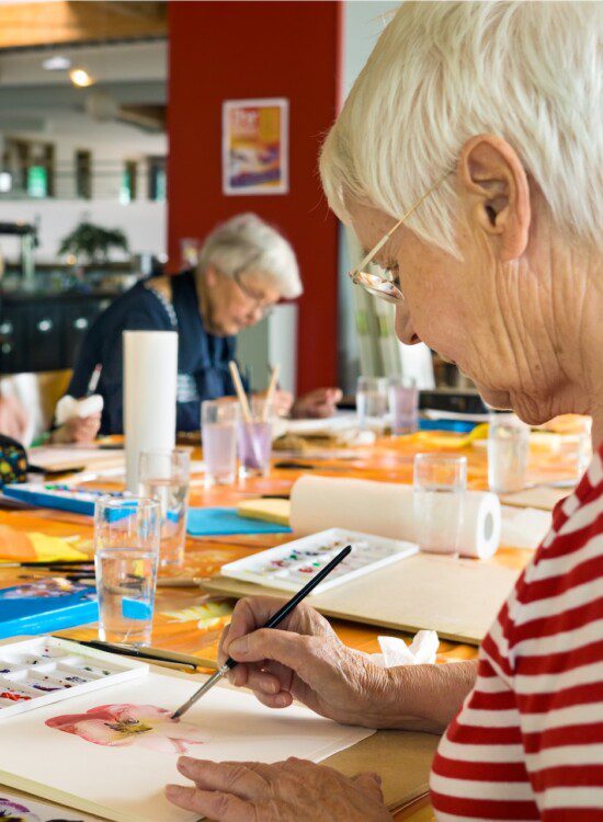 Group of seniors take painting class at their senior living community