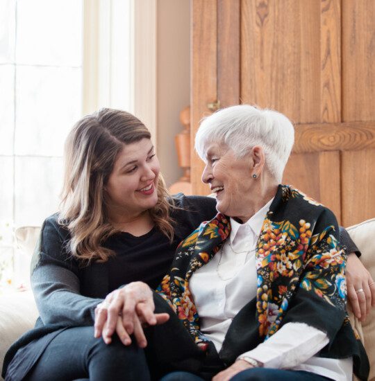 two senior women smile and high-five after winning a board game with friends