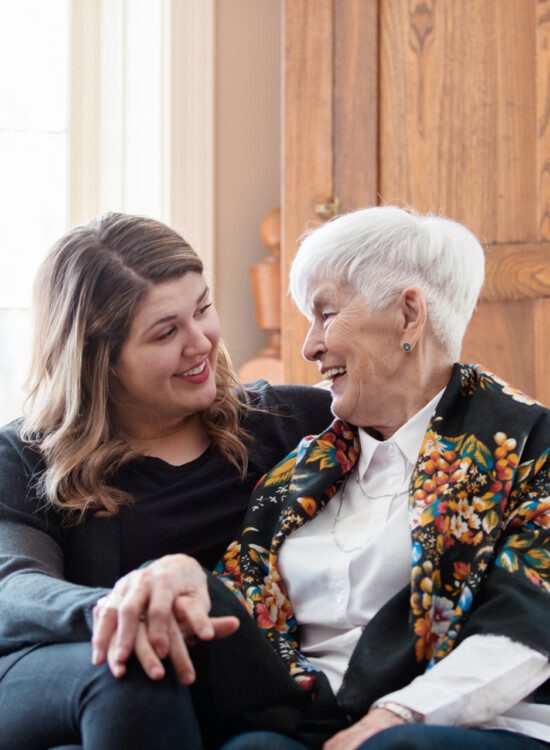 two senior women smile and high-five after winning a board game with friends