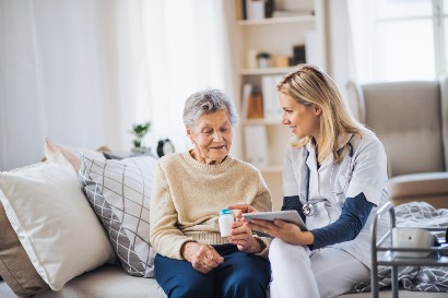 healthcare worker showing an elderly woman which prescriptions to take