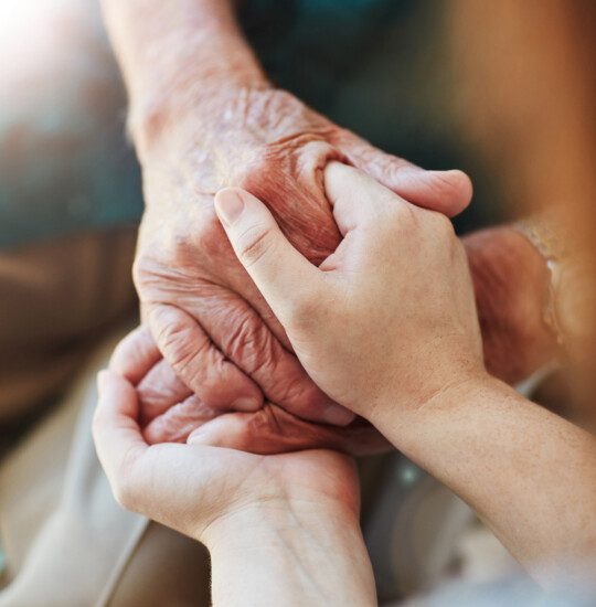 close-up of senior man holding hands with his adult daughter