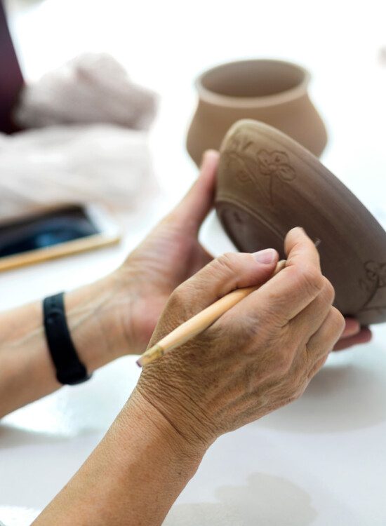 senior uses caring tool to cut designs into clay bowl
