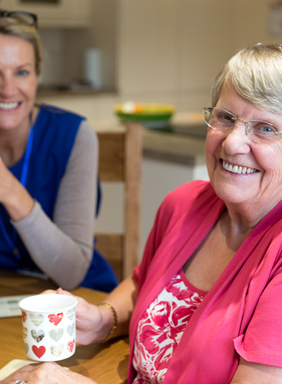 Senior woman smiles with caretaker at Senior Living Community