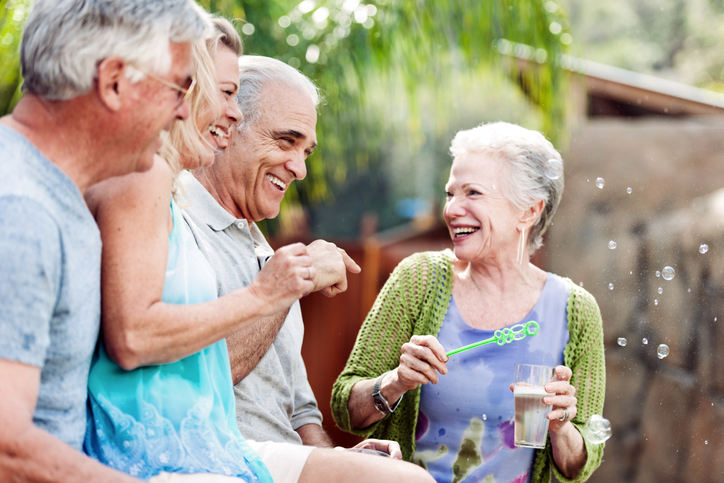 group of senior friends laugh and blow bubbles outdoors