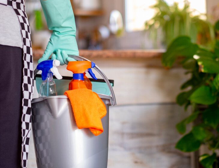 close-up of gloved hand carrying a bucket of cleaning supplies