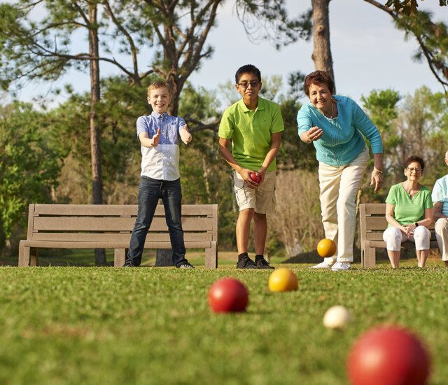 group of seniors and their grandchildren play bocce ball outside