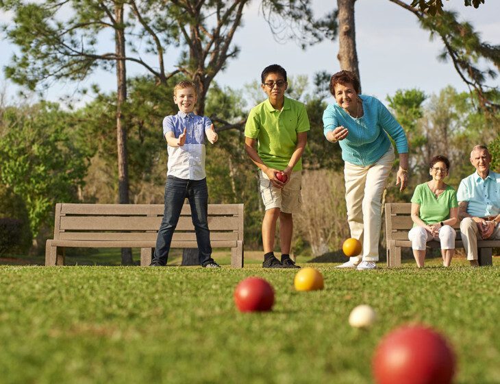 group of seniors and their grandchildren play bocce ball outside