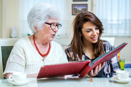elderly woman and adult woman looking through a photo album together