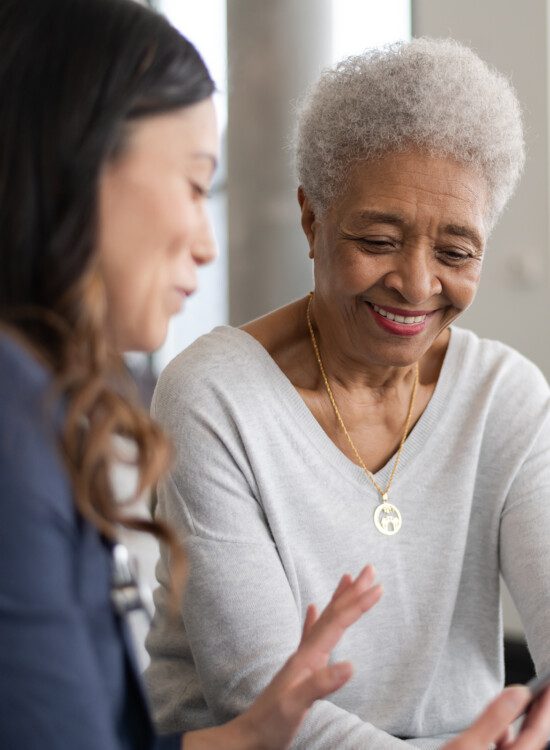 senior woman is shown information by her caretaker while seated