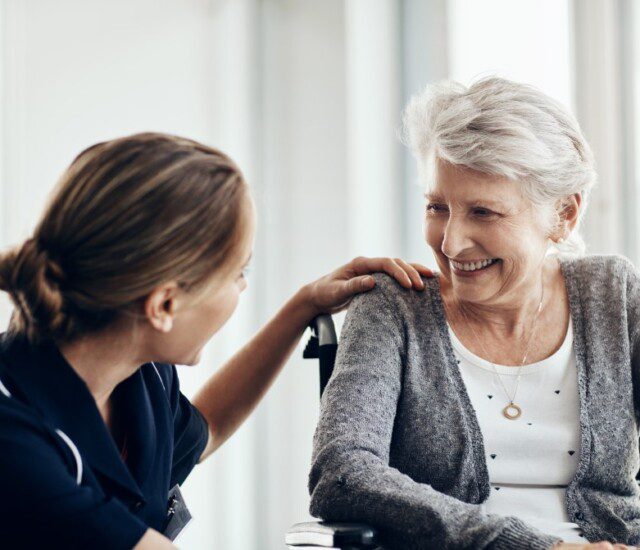 senior woman in wheelchair with nurse, both smiling