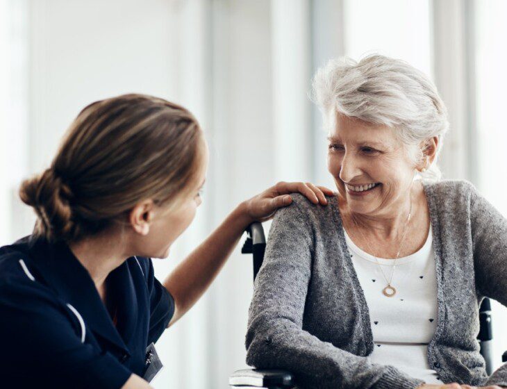 senior woman in wheelchair with nurse, both smiling