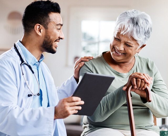 seated senior woman with can smiles while looking at test results with her smiling doctor