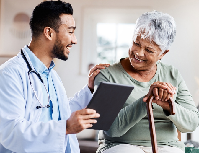 seated senior woman with can smiles while looking at test results with her smiling doctor