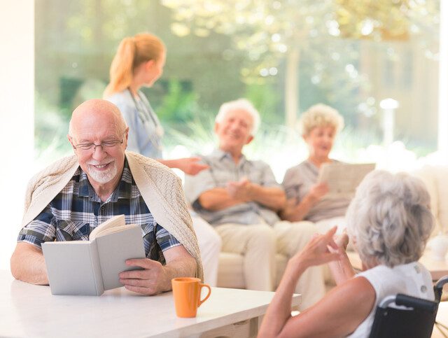 group of seniors conversing, reading, and relaxing in different areas of a cozy lounge