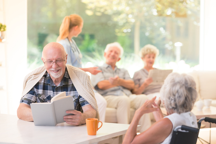 group of seniors conversing, reading, and relaxing in different areas of a cozy lounge