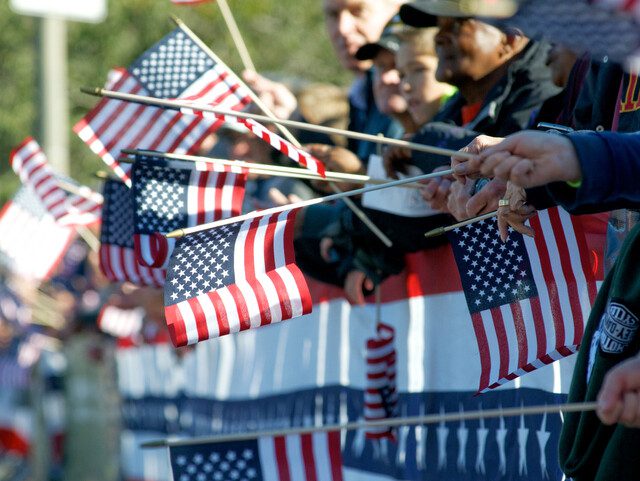 group of observers wave American flags during a parade