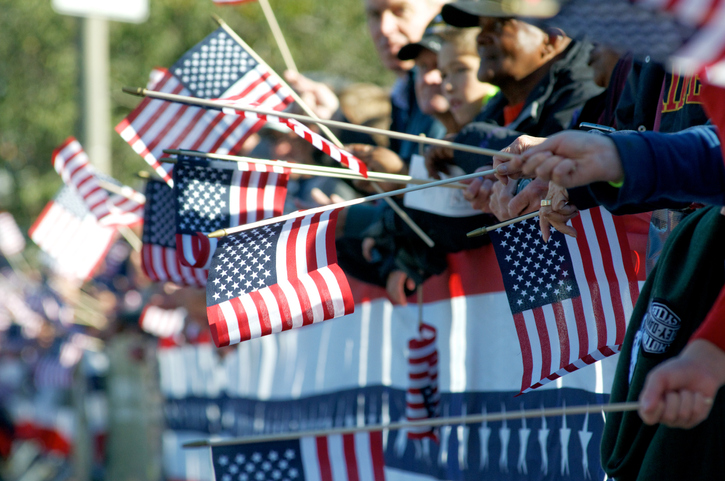 group of observers wave American flags during a parade