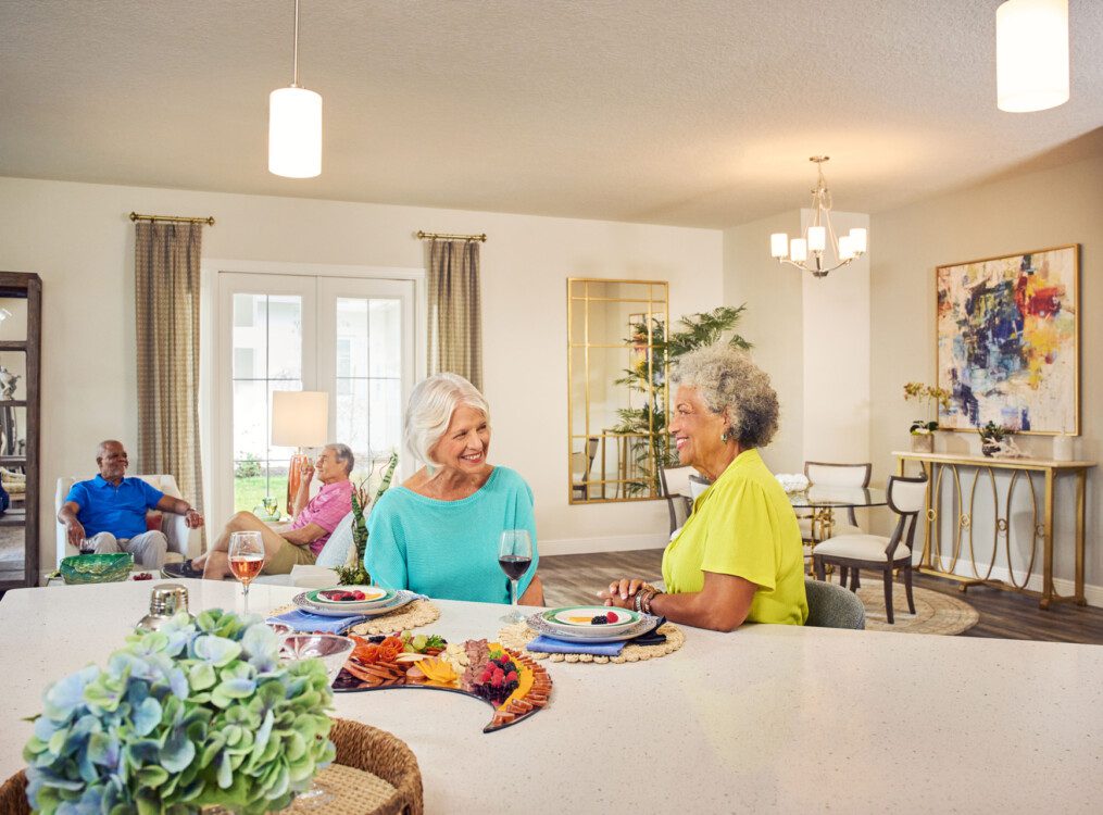 group of senior friends enjoy wine and dinner together in one of the villas at Village on the Green Senior Living Community