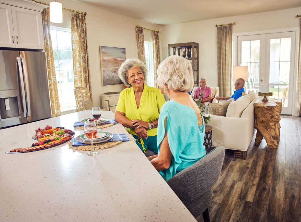 group of senior friends enjoy wine and dinner together in one of the villas at Village on the Green Senior Living Community