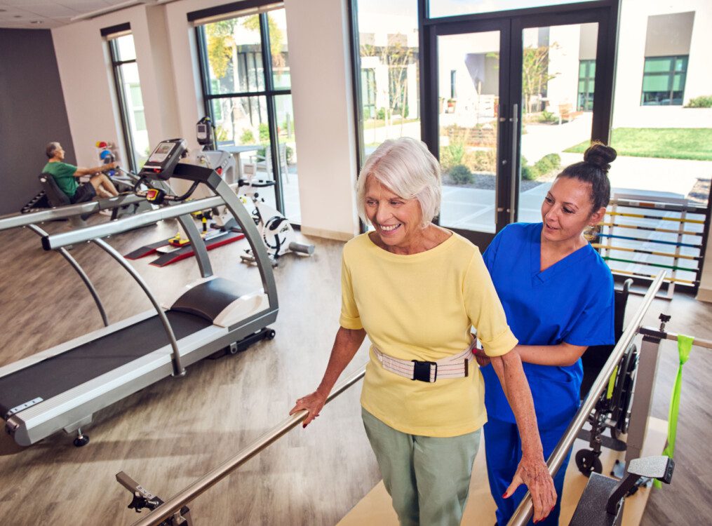 senior woman performs physical therapy exercise with the help of a PT in at Village on the Green Senior Living Community