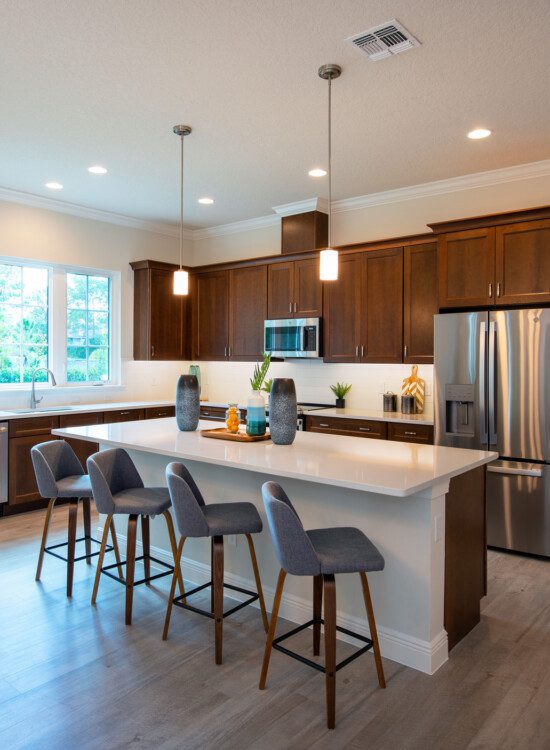 open-concept kitchen with island and chairs in senior villa home at Village on the Green