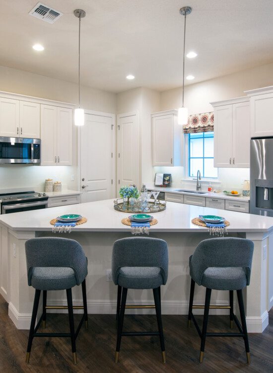 open-concept kitchen with island and chairs in senior villa home at Village on the Green